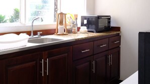 A kitchen with a window, a sink, a microwave, and dark wooden cabinets. - 3-bedroom apartment in Downtown San José (San José)