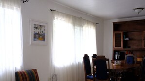 A living room with striped armchairs, a dining table with chairs, a ceiling fan, and a framed picture on the wall. - 3-bedroom apartment in Downtown San José (San José)