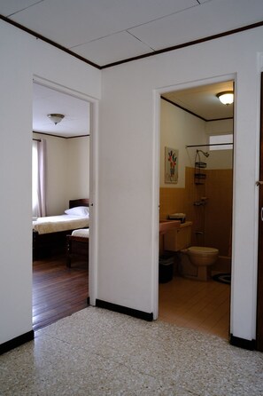 Une chambre d’hôtel avec un lit, une salle de bain avec des toilettes et une douche.
