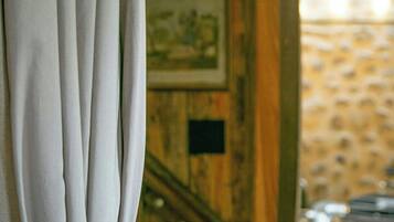 A room with a wooden wall, a framed picture, and a window with curtains.
