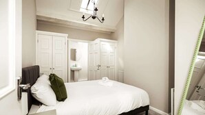 A bedroom with a bed, a bedside table, a mirror, and a wardrobe. - Central Chester Recently Renovated 1BR Flat (Chester)
