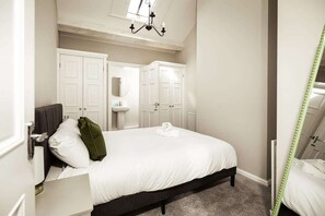 Ein Schlafzimmer mit Bett, Nachttisch, Spiegel und Kleiderschrank.