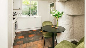 A compact kitchen with white cabinets, a black countertop, and a round table with chairs. - Central Chester Recently Renovated 1BR Flat (Chester)