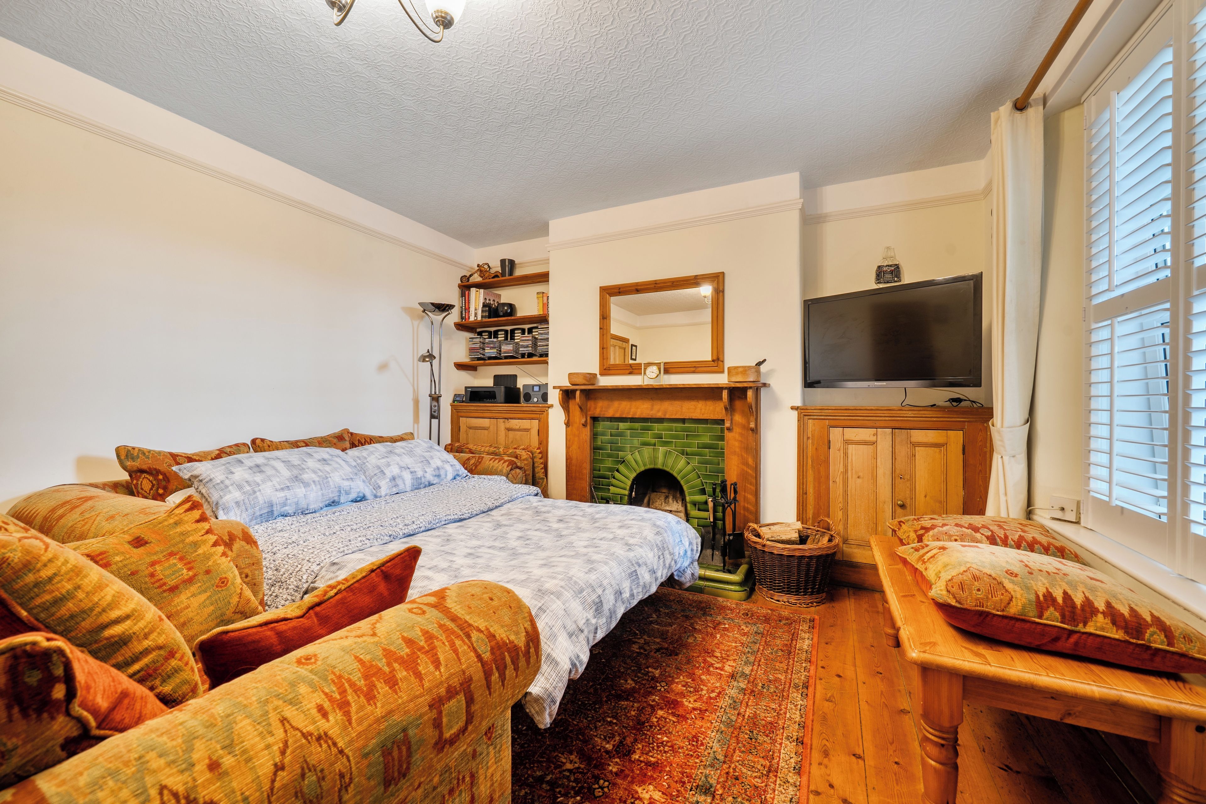A cozy room with a bed, a television, a fireplace, and a bookshelf.