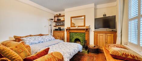 A cozy room with a bed, a television, a fireplace, and a bookshelf.