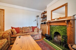 A living room with a wooden sofa, a coffee table, a fireplace, and a bookshelf.