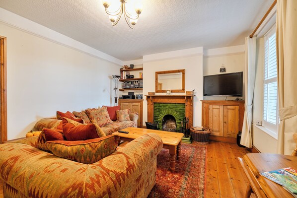 Una sala de estar acogedora con un sofá, chimenea, televisor y estantería.