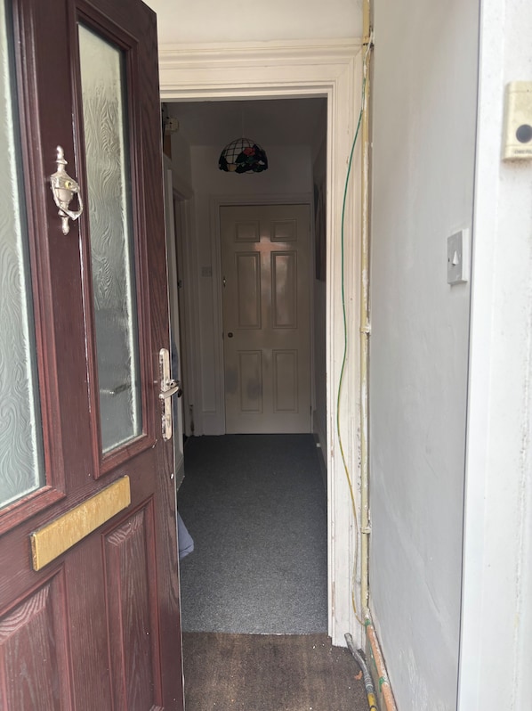 A hallway with a wooden door, a white door, and a doormat.
