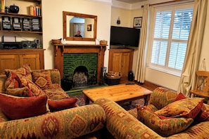 A cozy living room with a fireplace, a television, and a bookshelf. - 1 Bed - Sleeps 4 - Parking - Pets - Town Centre (Wadebridge)