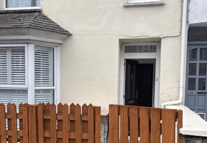 A building with a bay window, a door, and a wooden fence.
