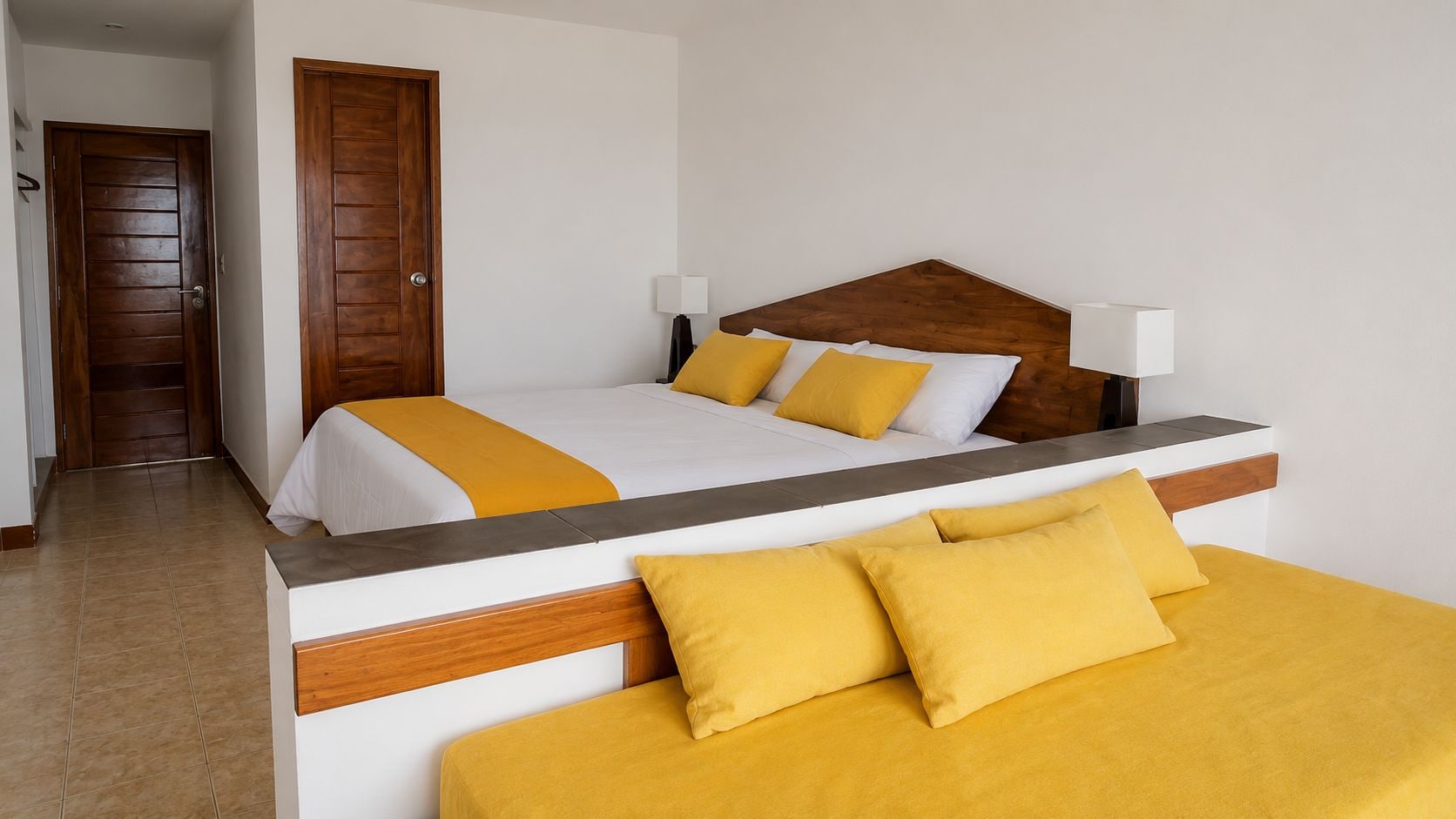 Une chambre d’hôtel avec deux lits, une porte en bois et un sol carrelé.