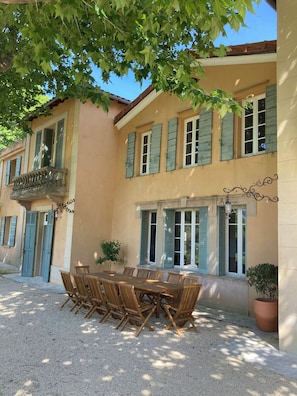 A building with a balcony, a dining area with a table and chairs, and a potted plant. - 17th century estate near Aix-en-Provence (Aix-en-Provence)