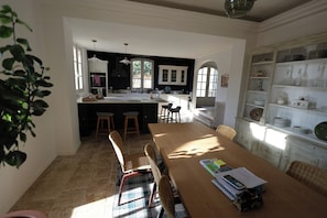 A spacious dining area with a long wooden table, wicker chairs, and a view of the kitchen. - 17th century estate near Aix-en-Provence (Aix-en-Provence)