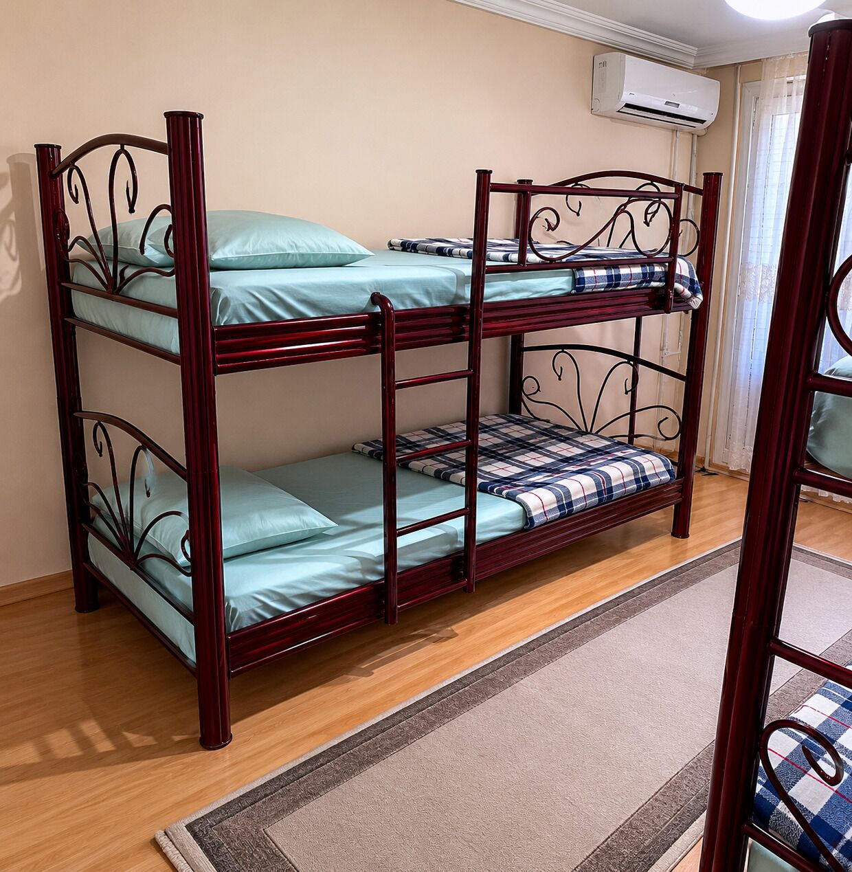 A bunk bed with a ladder, a window with curtains, and an air conditioning unit on the wall.