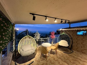 A terrace with a wicker chair, a round table, and a sofa.