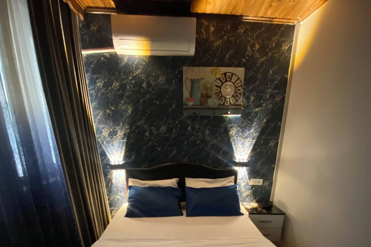 A bed with a blue and white bedspread, two pillows, and two rolled towels.