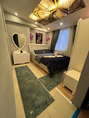 Un dormitorio con cama, cómoda, silla, espejo y lámpara en el techo.