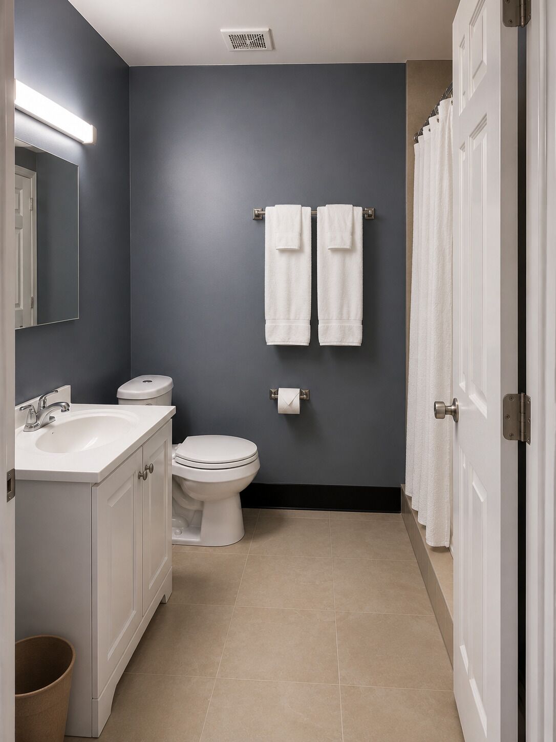 Un baño con lavamanos blanco, inodoro y dos toallas colgadas en la pared.
