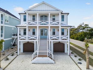 A two-story house with a front porch, a staircase, and two garage doors.