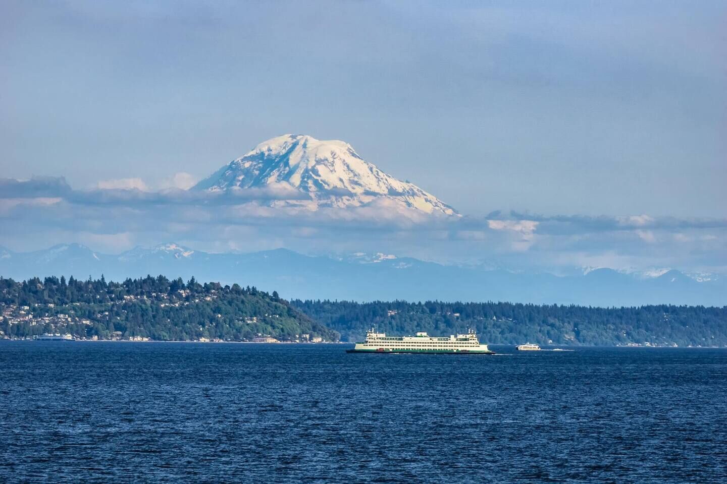 A cruise ship on a body of water with a mountain in the background.