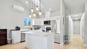 A modern kitchen with white cabinetry, a large island, stainless steel appliances, and pendant lighting. - Bright 3BR/2BA Retreat Near UW & Northgate Station (Seattle)