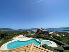 A resort with a large pool, manicured gardens, and a view of the sea and mountains. - EXCLUSIVE SHERDEN (Golfo Aranci)