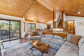 Ein geräumiges Wohnzimmer mit einer großen Eckcouch, einem Holztisch und einer Treppe, die in einen oberen Bereich führt.