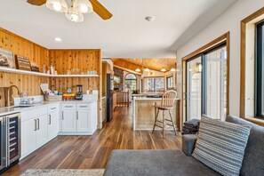 Eine geräumige Küche mit Holdekor, ein Essbereich mit Holztisch und -stühlen sowie eine gemütliche Sitzecke mit Sofa und Fenster.