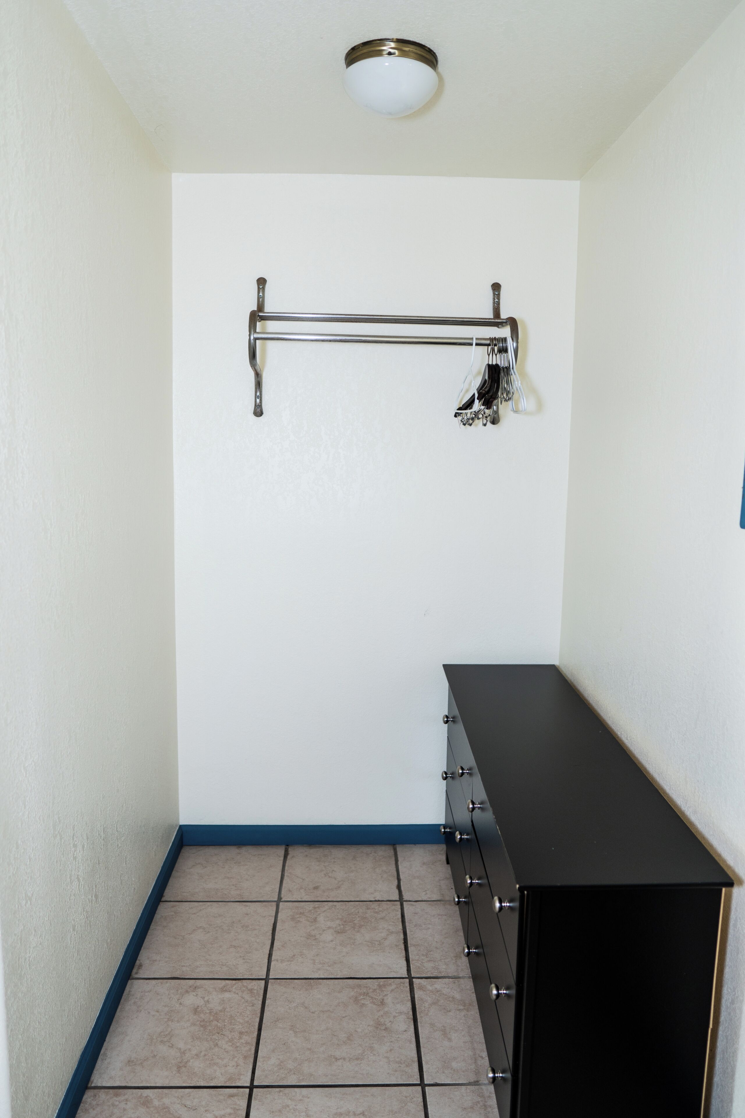 Een kleine badkamer met betegelde wanden, een zwart wastafelmeubel, een handdoekrek met handdoeken en een plafondlamp.