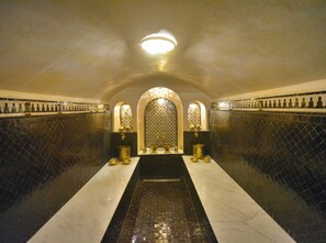 A tiled bathroom with a central sink, two wall-mounted lights, and a patterned wall design. - Dar Arwa & Spa (Marrakech)
