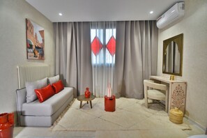 A modern living room with a sofa, a small table, a mirror, and a radiator. - Dar Arwa & Spa (Marrakech)