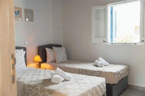 Ein Hotelzimmer mit zwei Betten, einem Fenster und einer Lampe.