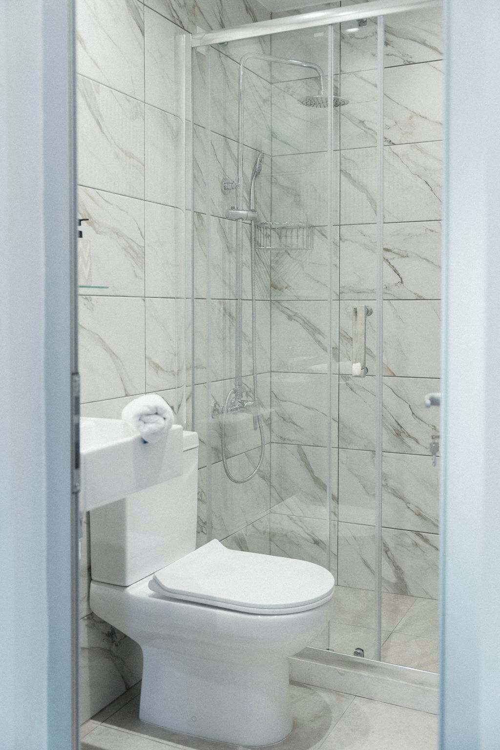 Une salle de bain équipée de toilettes, d’une douche et de carreaux de marbre.