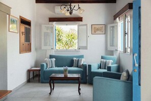 A living room with a sofa set, a coffee table, and a window with a view of greenery. - Charming 2BR Village Getaway Near the Beach (Agios Theodoros Larnakas)