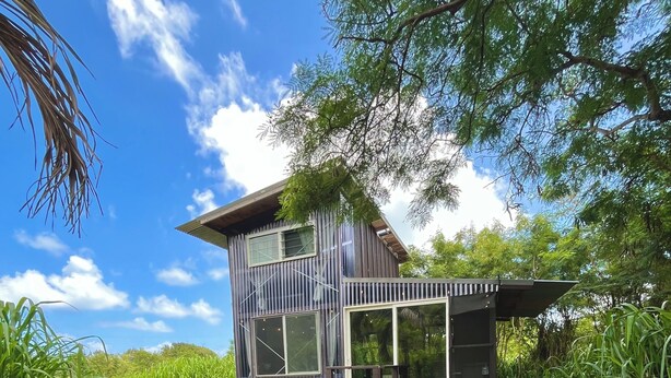 A modern house with a patio, a table, and two chairs.