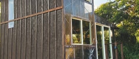 A wooden cabin with a sloped roof, large windows, and a small porch area.