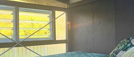 A bedroom with a bed, a window, and a wooden ceiling.