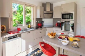 Eine moderne Küche mit Geschirrspüler, doppelter Spüle, Edelstahlgeräten und einer Frühstücksvorrichtung mit Croissants, Beeren und Kaffee.