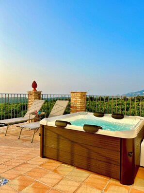Un jacuzzi en una terraza con vistas al mar y la vegetación.