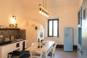 Una cocina con una mesa de comedor, sillas, un refrigerador y una ventana.