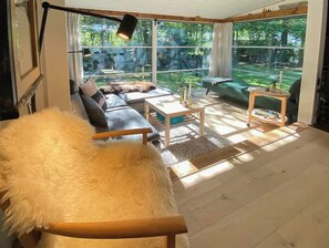 A modern living room with a sofa, coffee table, and a fluffy white chair. - House in Skæring near city and nature (Egå)