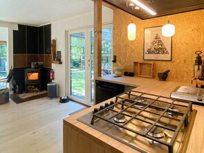 A modern kitchen with a wood-burning stove, a gas stove, and a large window. - House in Skæring near city and nature (Egå)