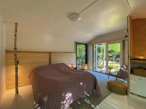 A bedroom with a bed, a wooden wall, a window, and a door leading to an outdoor area. - House in Skæring near city and nature (Egå)
