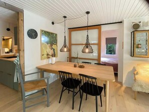 A dining area with a wooden table, black chairs, pendant lights, a clock, and a painting on the wall. - House in Skæring near city and nature (Egå)