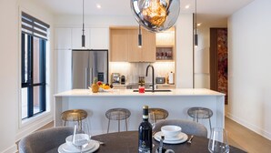 A modern kitchen with a central island, stainless steel appliances, and pendant lighting.