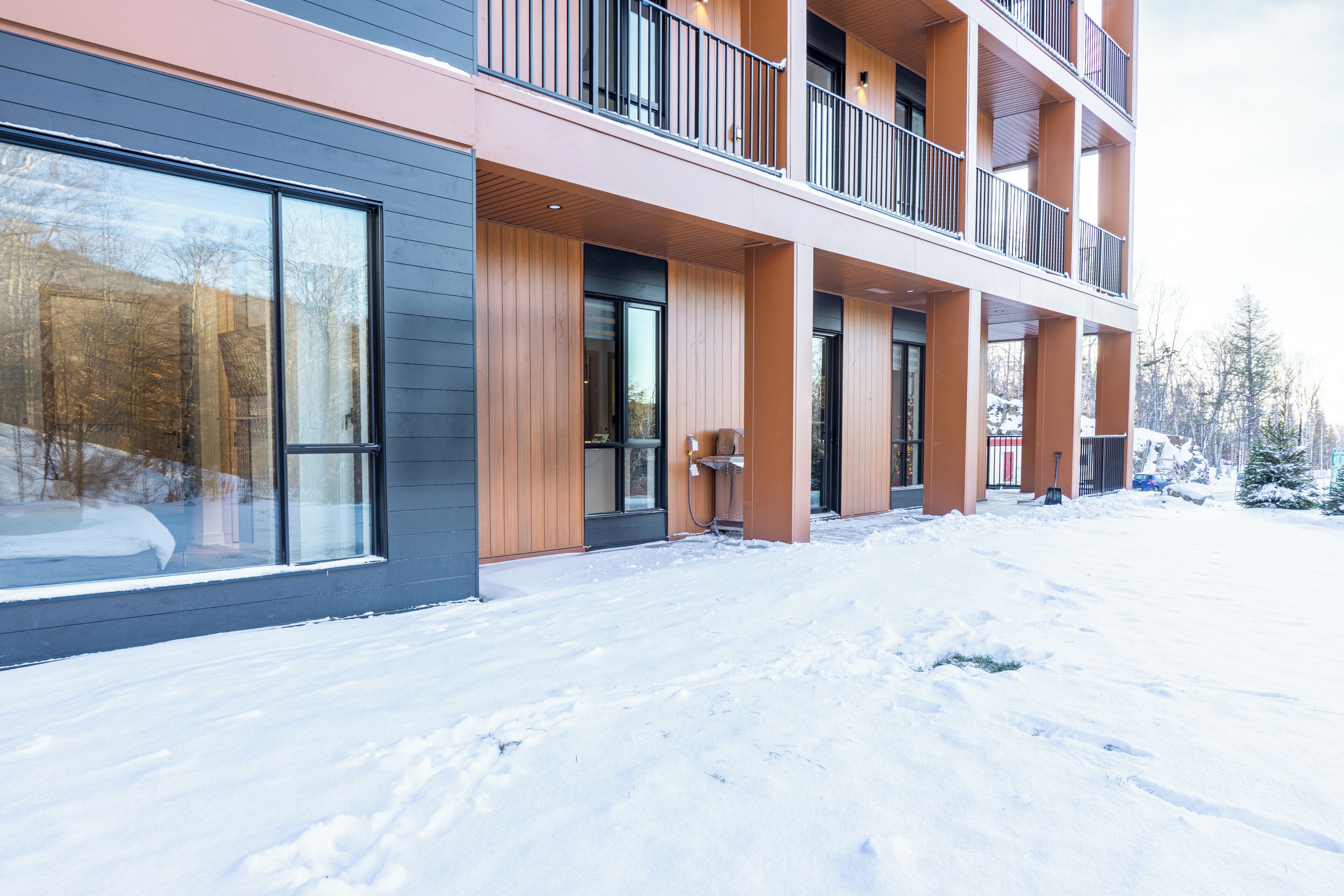 Un immeuble à plusieurs étages, doté de grandes fenêtres, de balcons et dont le sol est recouvert de neige.