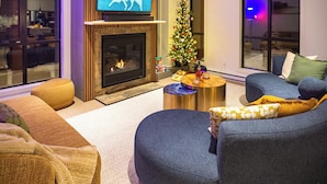 A modern living room with a fireplace, a television, a Christmas tree, and comfortable seating.