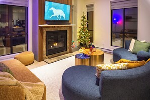 Een moderne woonkamer met een open haard, een televisie, een kerstboom en comfortabele zitplaatsen.