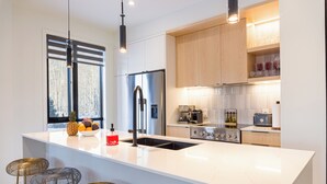 A modern kitchen with a large island, stainless steel appliances, and a window with a view.