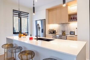 Een moderne keuken met een groot eiland, roestvrijstalen apparatuur en een raam met uitzicht.